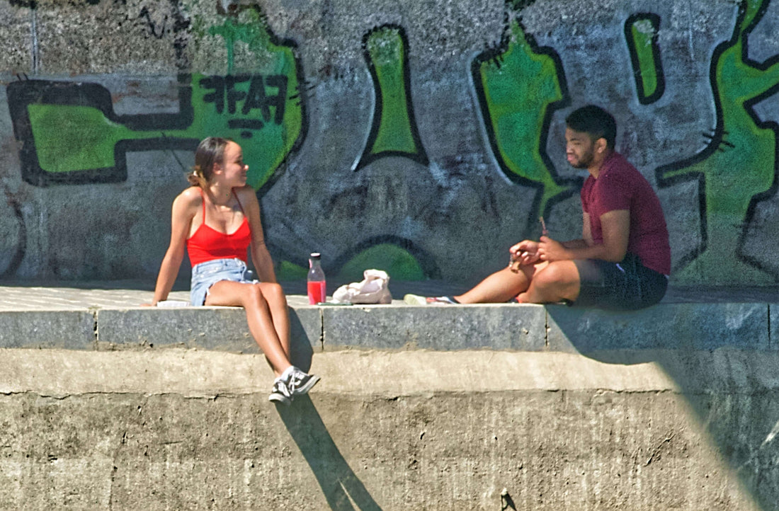 Agosto urbano: lo que realmente se lleva en la calle. Dos personas conversando junto a un mural colorido.