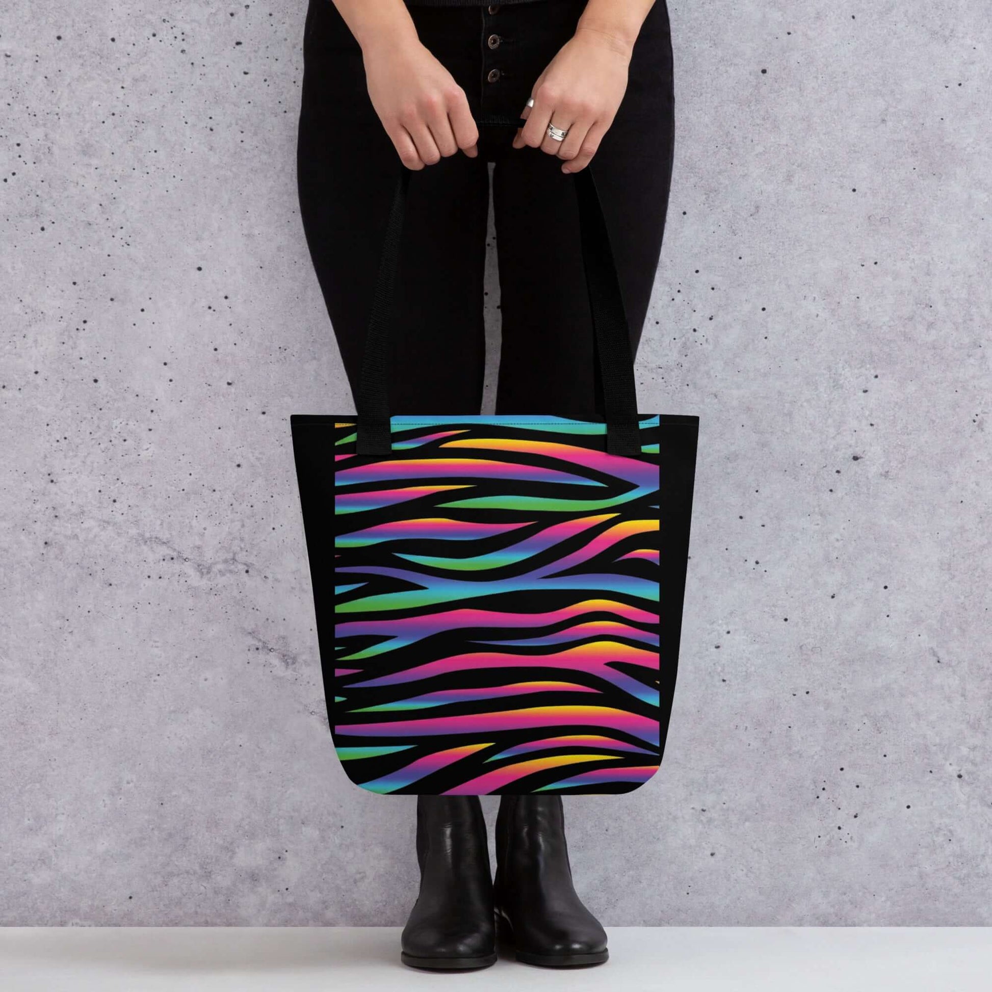 Bolsa CEBRA COLORES URBAN en mano, diseño de rayas vibrantes sobre fondo negro, ideal para un estilo streetwear.